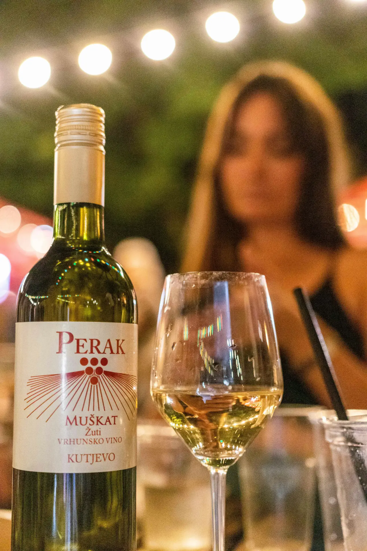 Glass of white wine served at a table under string lights